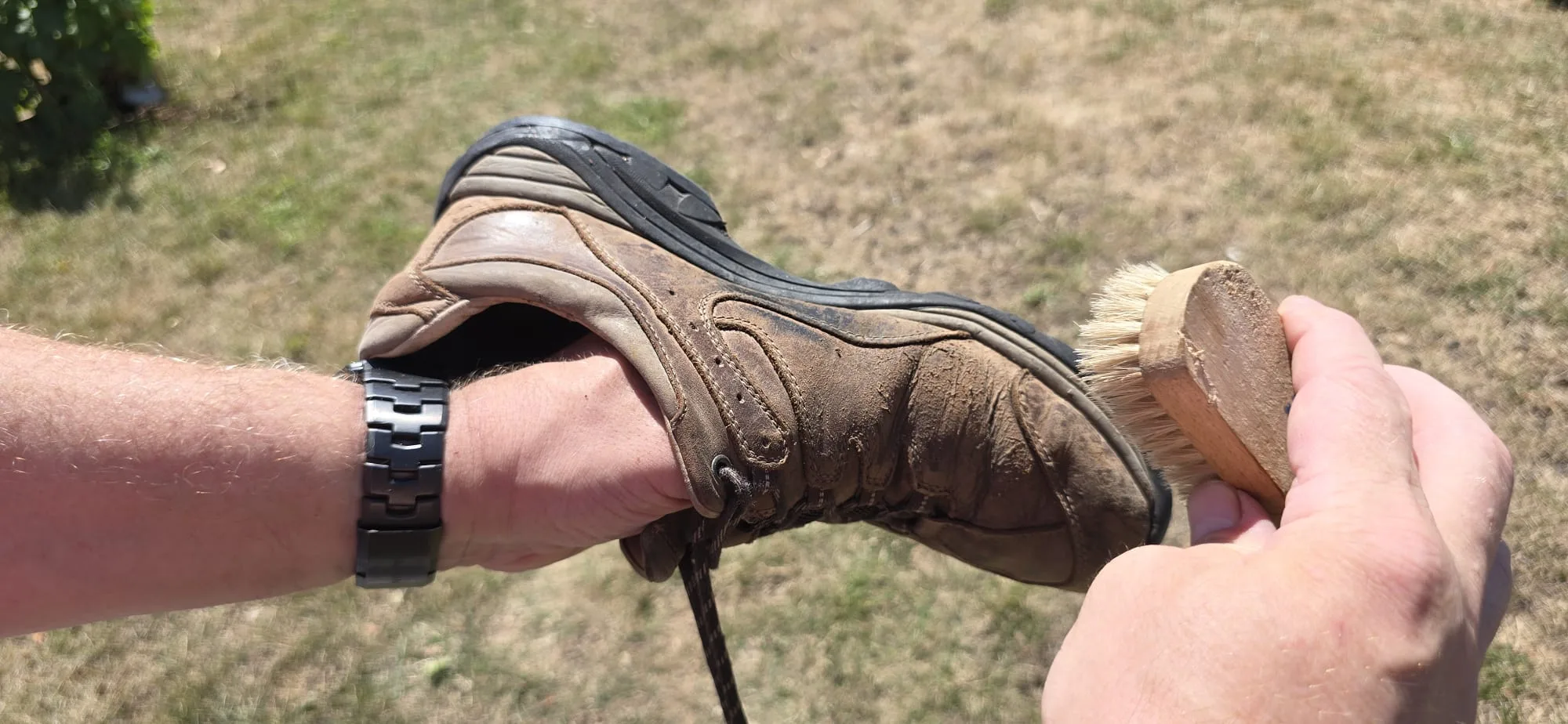 Brossage d'une chaussure de randonnée en cuir Gore-Tex avec une brosse à poils souples pour éliminer la poussière avant l'entretien.