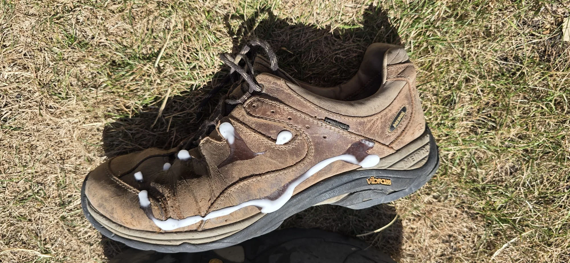 Application d'une crème nourrissante sur une chaussure de randonnée en cuir Gore-Tex afin de préserver la souplesse du cuir et la respirabilité de la membrane.