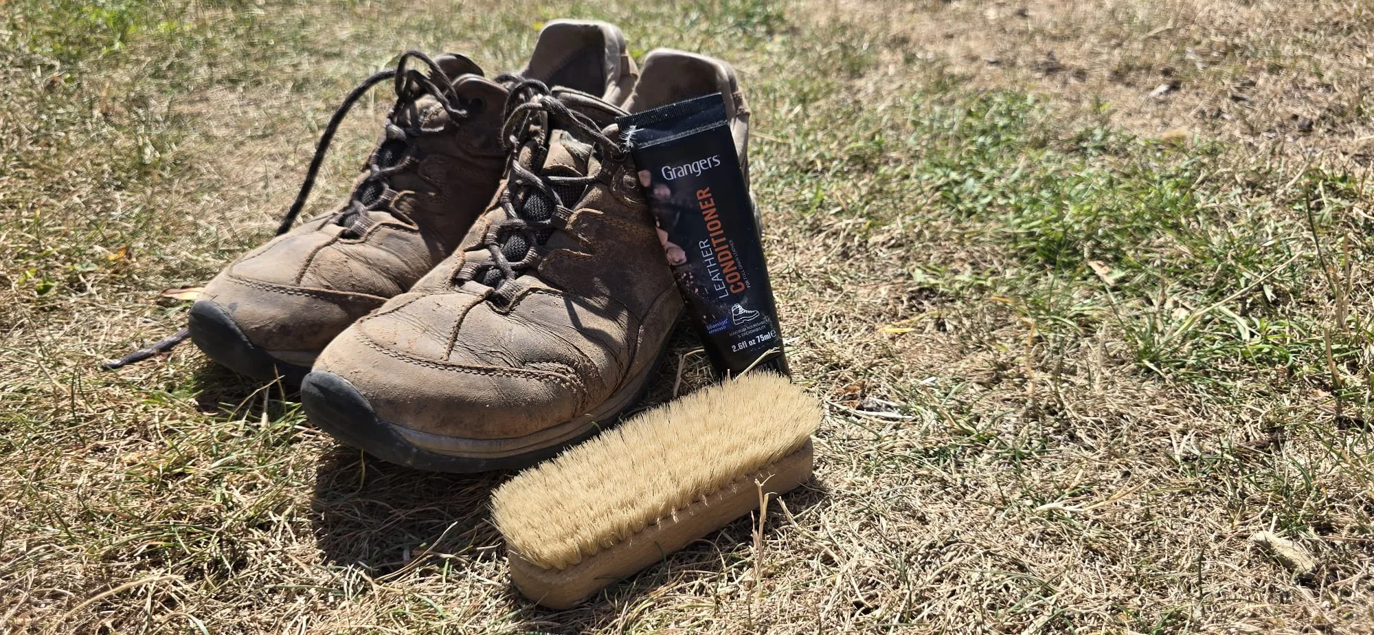 Chaussures de randonnée en cuir Gore-Tex posées au bivouac avec une brosse et une crème d'entretien avant le nettoyage du soir.