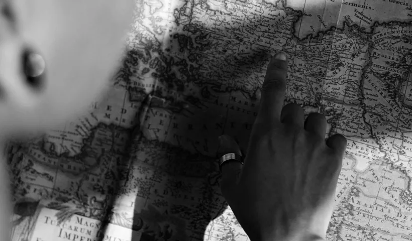 Main cherchant une destination sur une carte ancienne