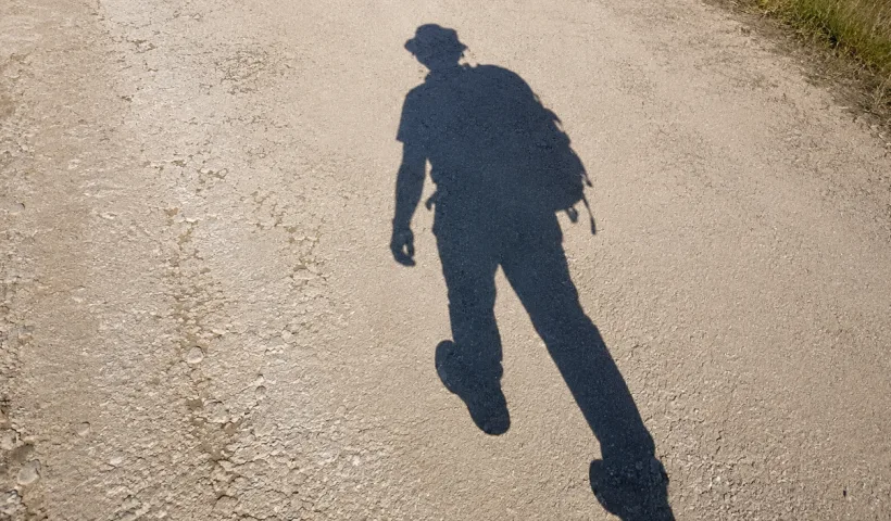 Ombre d'un randonneur marchant sur un sentier de la Rota Vicentina, dans le sud du Portugal.