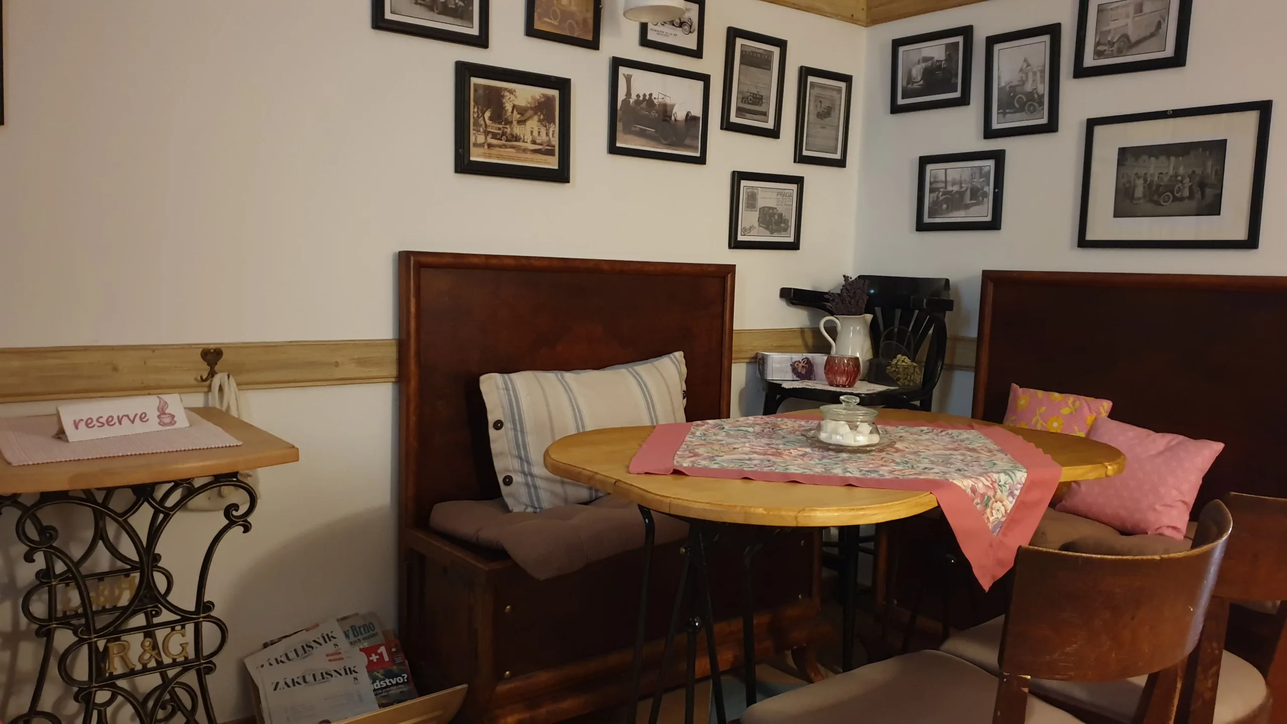 Intérieur chaleureux du Cosmai Café à Prague, avec ses banquettes en bois, ses coussins colorés et ses photographies anciennes aux murs.