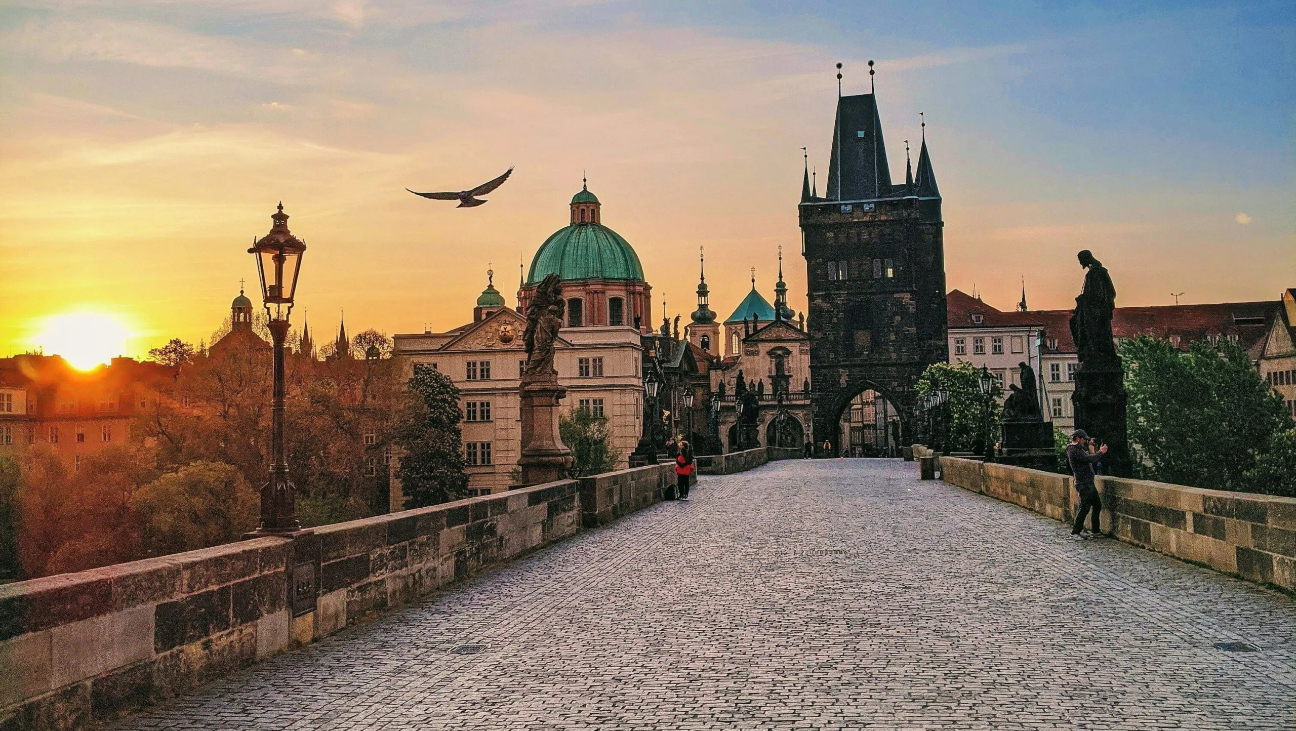 Le pont Charles à Prague au lever du soleil, avec ses statues baroques et la tour de la Vieille-Ville.