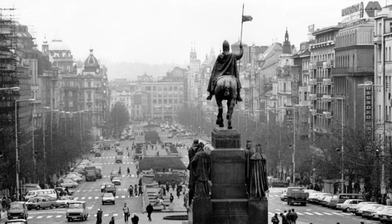 Vue historique en noir et blanc de la place Venceslas à Prague, avec la statue équestre de saint Venceslas et des voitures d'époque.