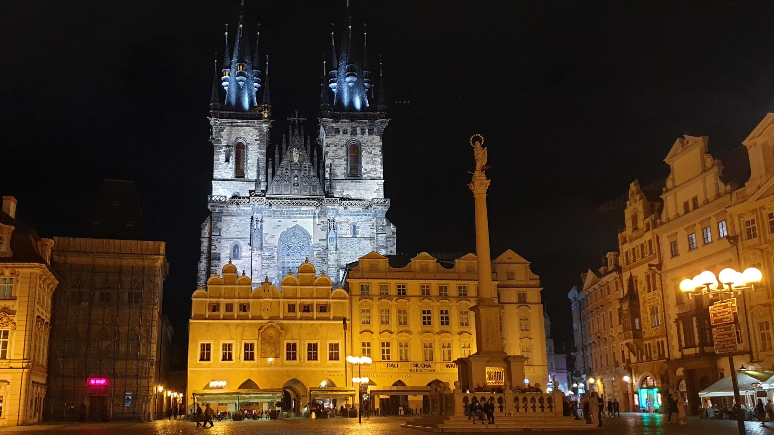 L'église Notre-Dame du Týn illuminée domine la place Staroměstské náměstí à Prague, de nuit.