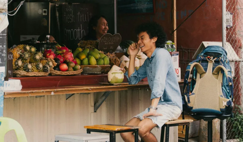 Un voyageur échange avec une vendeuse à un stand de fruits à Chiang Mai