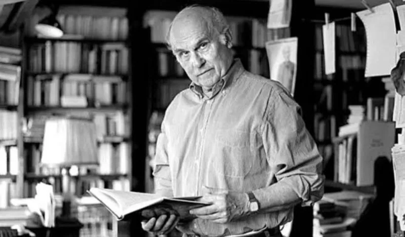 Ryszard Kapuściński dans sa bibliothèque, tenant un livre. Portrait du journaliste et écrivain polonais, auteur de Mes voyages avec Hérodote.